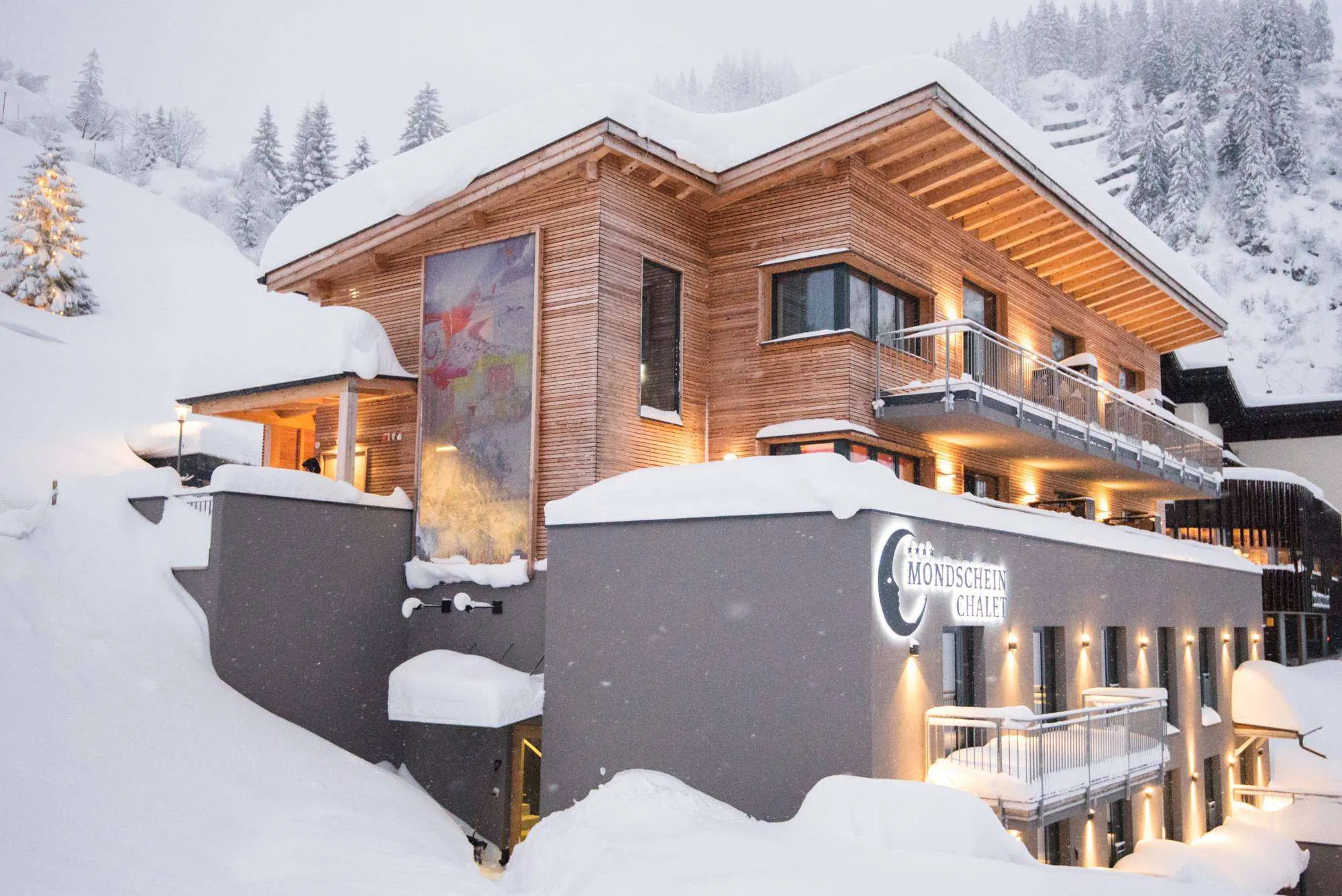 The Mondschein Chalet in falling snow, lit at dusk