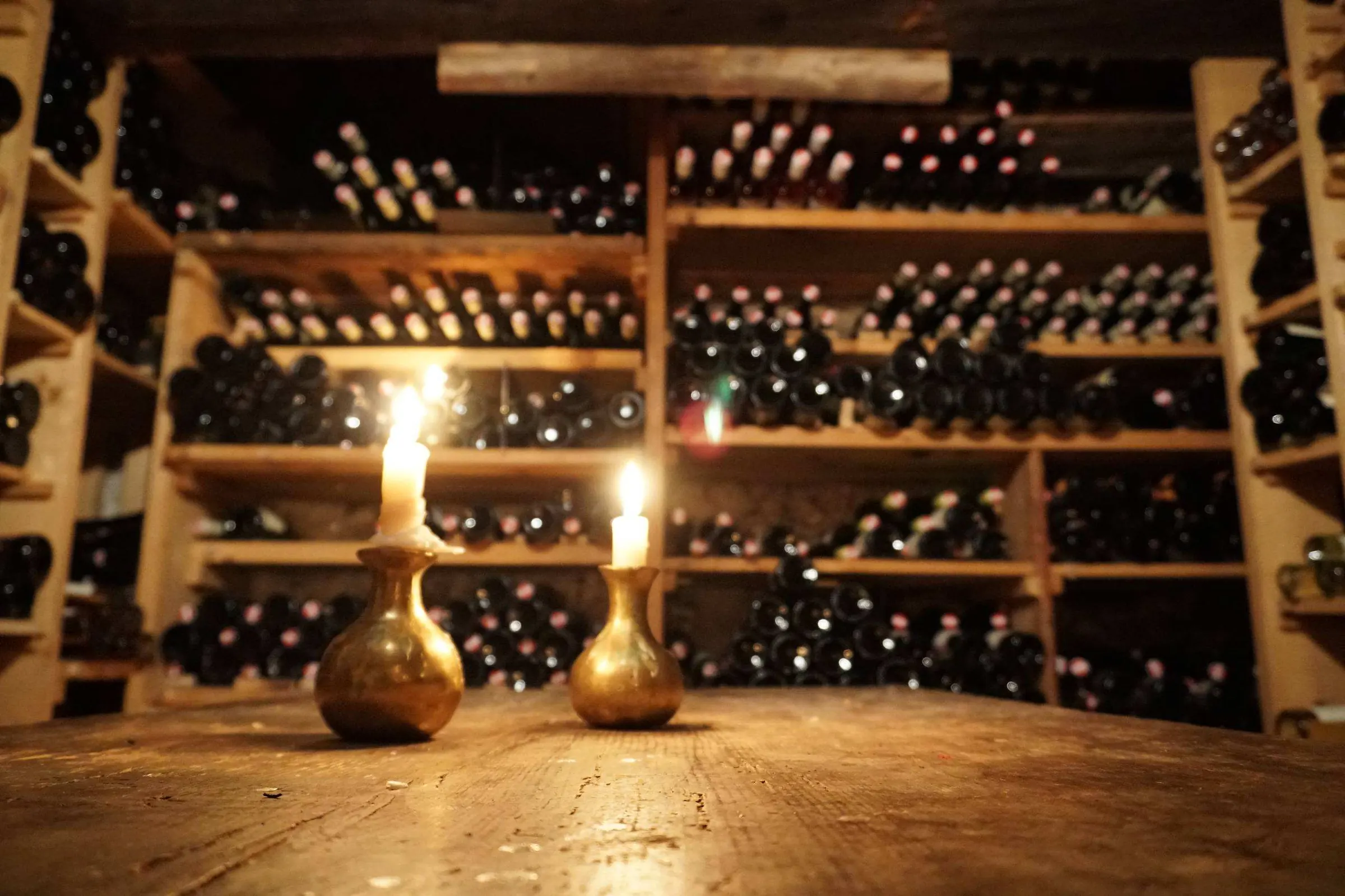 Kerzenlicht vor vollen Weinregalen