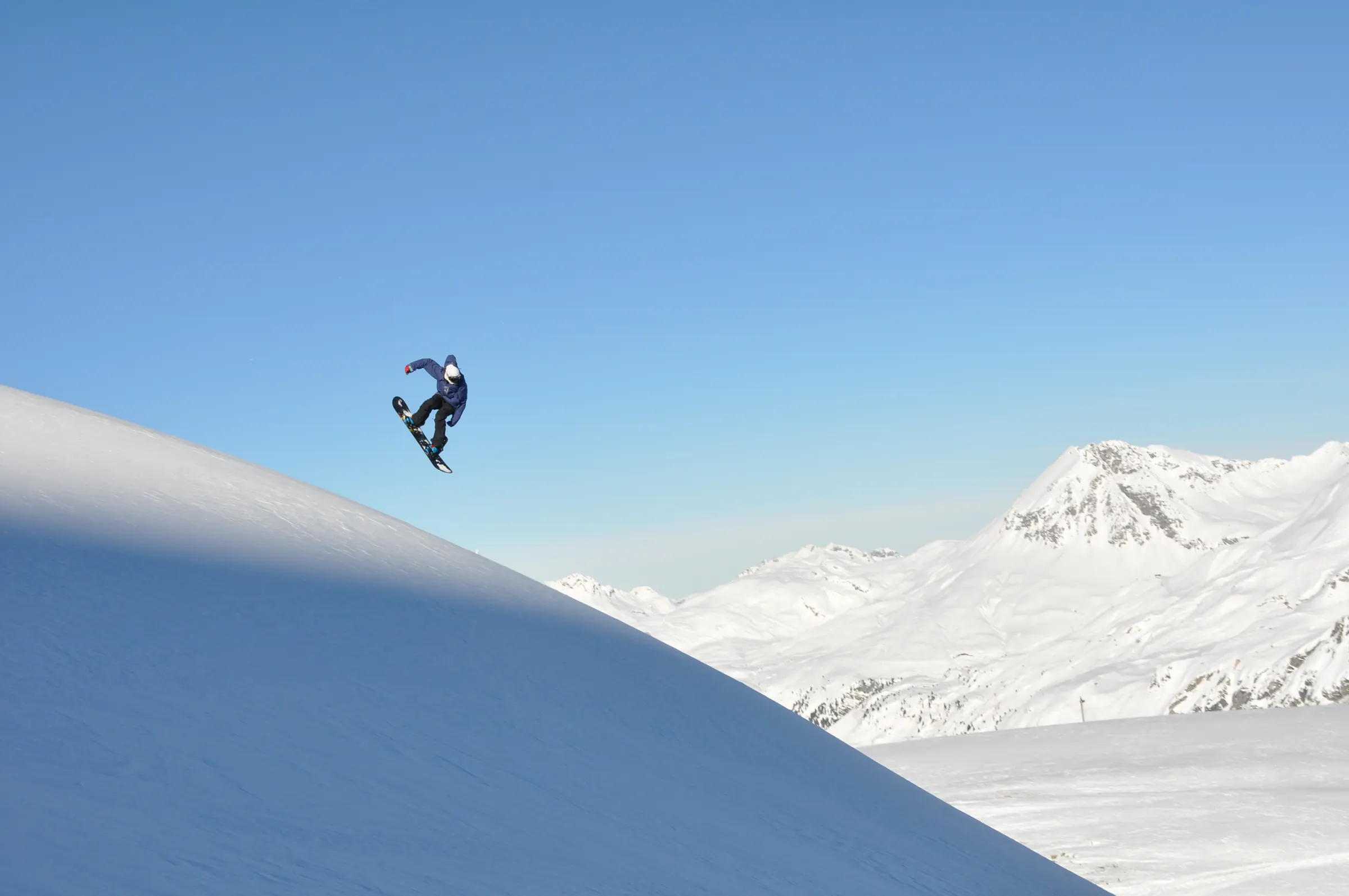 Snowboarder im Sprung über einer Schneekante